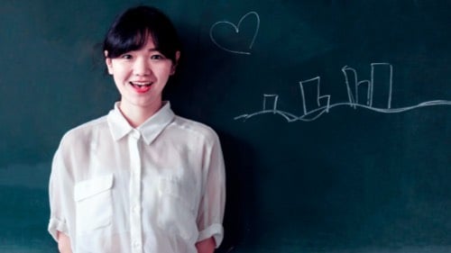 A teacher speaking in front of a chalk board