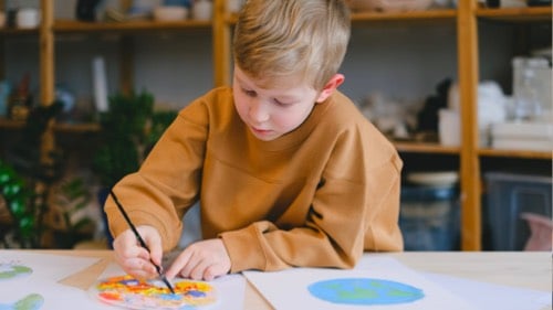 A young boy paints the countries of the world on paper