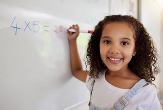 Photo of a student writing a math equation on a whiteboard